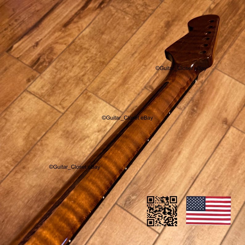May include: A close-up of a guitar neck with a flamed maple finish. The neck is a rich, warm brown color with a glossy sheen. The headstock has tuning pegs. The image includes a QR code and the American flag.