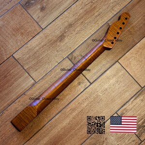 May include: A wooden guitar neck with a natural finish. The neck has a headstock with tuning peg holes and a smooth, polished surface. The wood grain is visible, and the neck is angled. The image includes a QR code and an American flag.