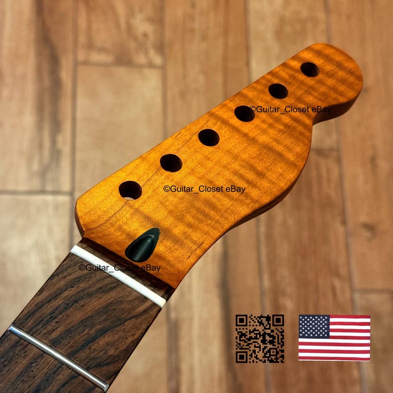 May include: A close-up of a guitar neck and headstock. The headstock is a warm, amber color with dark circular tuning holes. The fretboard is a dark brown with silver frets. The text "Guitar_Closet eBay" is visible. An American flag is in the lower right corner.