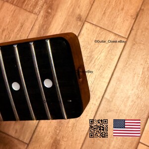 Op de afbeelding: Close-up van een gitaarhals met een donkere toets en zilveren frets. Twee witte fretmarkers zijn zichtbaar. Het hout heeft een warme, bruine tint. De afbeelding bevat de tekst "Guitar_Closet eBay", een QR-code en de Amerikaanse vlag.