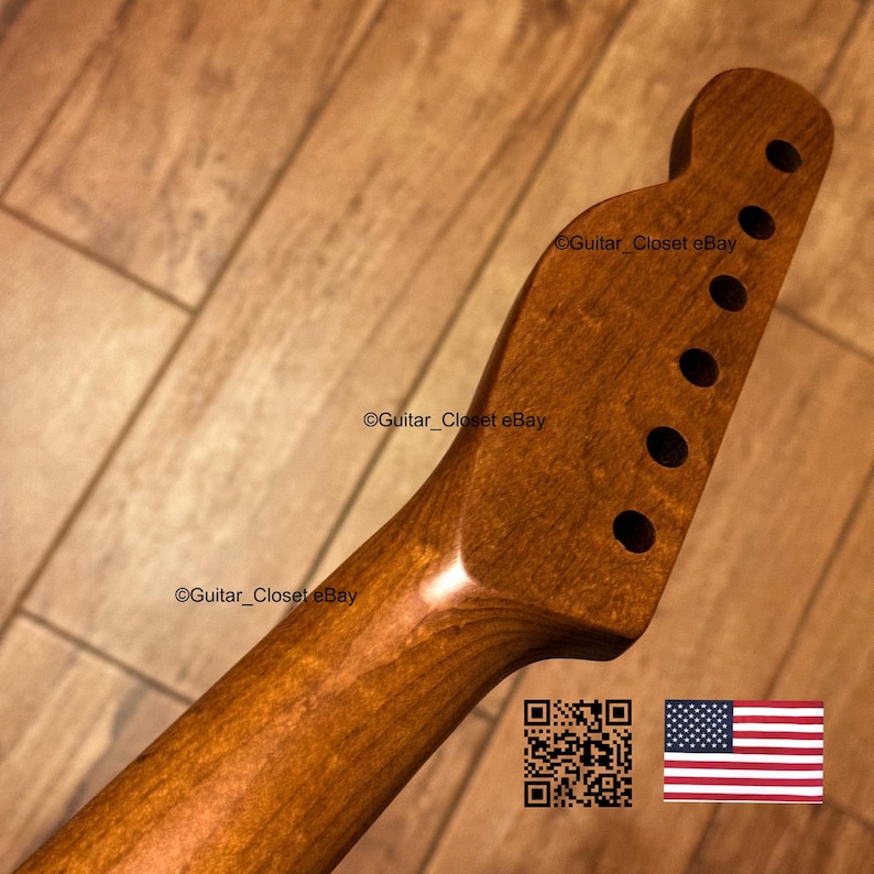 May include: A natural-toned wooden guitar neck featuring a smooth, polished finish and a headstock with six pre-drilled tuning peg holes arranged in a single row. The wood grain is visible throughout the surface of the neck and headstock.