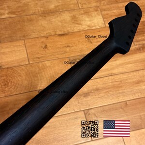 Peut inclure: Manche de guitare noir avec chevilles d'accordage. Le manche est en bois et a une finition lisse et sombre. L'image comprend un code QR et le drapeau am&eacute;ricain.