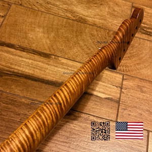 K&ouml;nnte beinhalten: Ein Gitarrenhals mit einer markanten Tigerstreifen-Flammenahorn-Holzmaserung und einem warmen bernsteinfarbenen Finish. Die Kopfplatte enth&auml;lt vorgebohrte L&ouml;cher f&uuml;r Stimmwirbel. Der Text Guitar_Closet eBay ist auf Hals und Kopfplatte sichtbar.