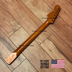 May include: A guitar neck made of light brown wood, featuring a headstock with six tuning peg holes. The neck has a smooth, polished finish and a rectangular end. The image includes a QR code and a US flag.