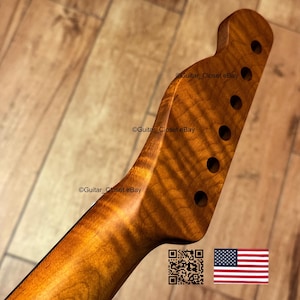 Puede incluir: Primer plano del m&aacute;stil y la pala de una guitarra de madera veteada. La veta de la madera tiene un patr&oacute;n arremolinado con un color &aacute;mbar c&aacute;lido. La pala tiene seis agujeros circulares para las clavijas.