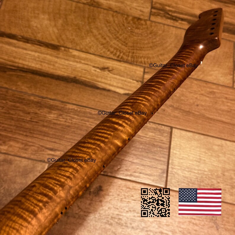 K&ouml;nnte beinhalten: Ein Gitarrenhals aus braunem Holz mit einer ausgepr&auml;gten Tigerstreifen-Flammenahorn-Maserung. Der Hals verf&uuml;gt &uuml;ber eine Kopfplatte mit sechs Mechanikbohrungen und kleinen schwarzen Seitenmarkierungen entlang der Griffbrettkante.