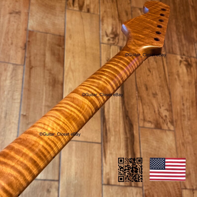 May include: A guitar neck with a flamed maple finish. The neck has a natural wood grain pattern and is angled towards the top of the image. The headstock has tuning peg holes. The text "Guitar Closet eBay" is visible on the neck.
