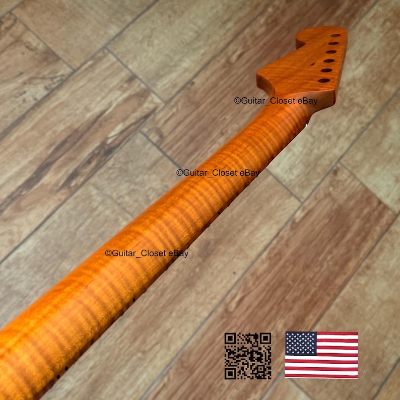 May include: A guitar neck with a flamed maple finish. The neck is a light amber color with a prominent wood grain pattern. The headstock has pre-drilled holes for tuning pegs. The image includes a QR code and the American flag.