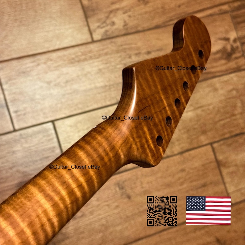 Puede incluir: Un m&aacute;stil de guitarra con una pala que presenta un patr&oacute;n de veta de madera de arce flameado con rayas de tigre. La pala tiene seis orificios preperforados para clavijas en una sola fila. El texto Guitar_Closet eBay es visible en la madera.
