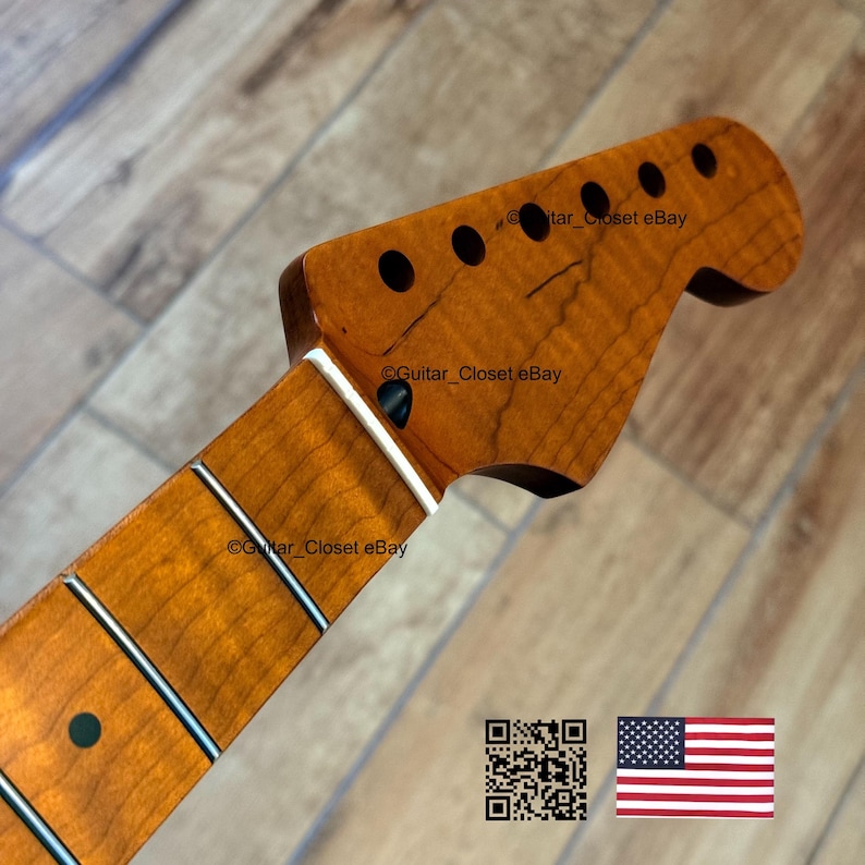 Puede incluir: Primer plano del m&aacute;stil y la pala de una guitarra. La madera tiene un tono &aacute;mbar c&aacute;lido con veta visible. La pala presenta seis agujeros negros para clavijas. El diapas&oacute;n tiene trastes plateados e incrustaciones de puntos negros. La imagen incluye un c&oacute;digo QR y una bandera estadounidense.