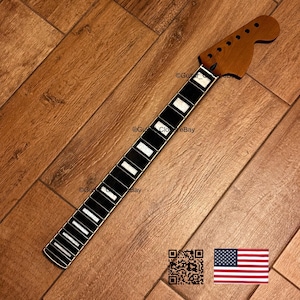May include: A guitar neck with a dark brown headstock and a black fretboard with white inlays. The neck is set against a wooden background. The image includes a QR code and a small American flag.