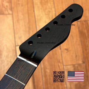 May include: A black guitar neck with six tuning peg holes and a dark wood fretboard. The headstock has a classic shape. The image includes a QR code and a small American flag.