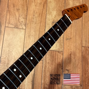 Puede incluir: M&aacute;stil de guitarra con diapas&oacute;n marr&oacute;n oscuro y pala m&aacute;s clara. El diapas&oacute;n tiene incrustaciones de puntos blancos y trastes plateados. La pala tiene agujeros para clavijas. La imagen incluye un c&oacute;digo QR y la bandera americana.