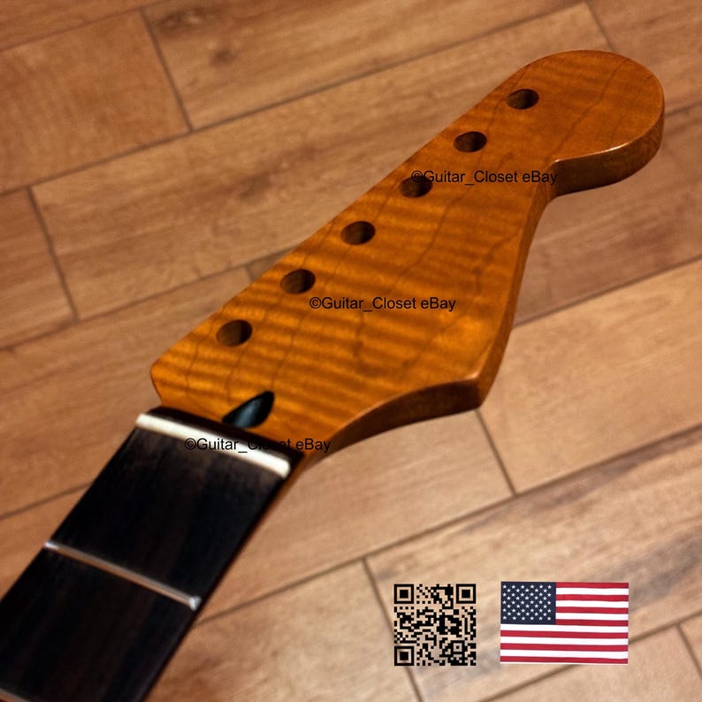May include: A guitar neck with a flamed maple headstock and a dark fretboard. The headstock has six tuning peg holes. The wood has a warm, amber color with visible grain patterns. The text "Guitar Closet eBay" is visible on the headstock. An American flag is in the image.