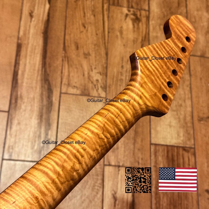Puede incluir: Un m&aacute;stil de guitarra de color marr&oacute;n claro con un patr&oacute;n de veta de madera de arce flameado con rayas de tigre. El clavijero tiene seis orificios para clavijas en una fila. El texto Guitar_Closet eBay es visible en el m&aacute;stil y el clavijero.