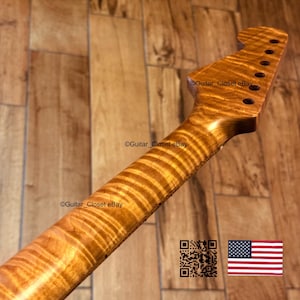 May include: A close-up of a guitar neck crafted from figured maple. The wood displays a unique grain pattern in warm, golden-brown tones. The headstock features tuning peg holes. The image includes the text "Guitar_Closet eBay" and a QR code.