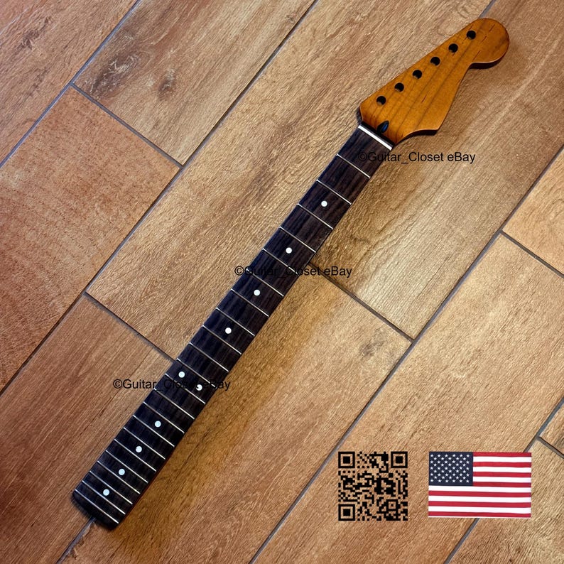 May include: A guitar neck with a dark fretboard and a light brown headstock. The fretboard has white dot inlays. The headstock has tuning peg holes. The image includes a QR code and an American flag.