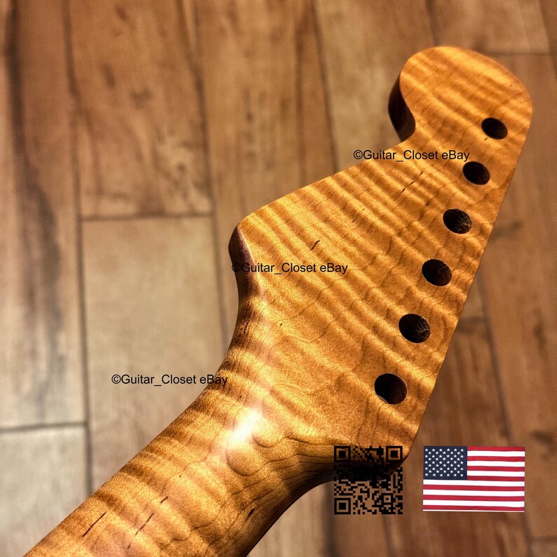 Puede incluir: Un clavijero de guitarra hecho de madera marr&oacute;n claro con un patr&oacute;n de grano de arce flameado con rayas de tigre. El clavijero presenta seis orificios circulares para las clavijas de afinaci&oacute;n alineados. El texto Guitar_Closet eBay es visible.