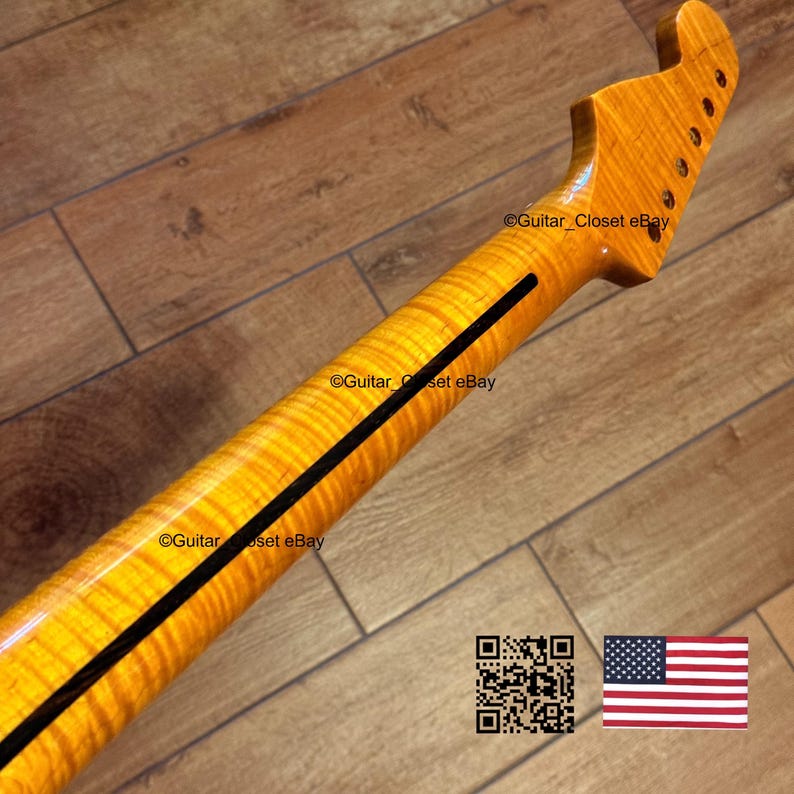 May include: Close-up of a guitar neck with a flamed maple finish. The neck has a dark stripe down the center and a headstock with tuning peg holes. The image includes a QR code and the American flag.