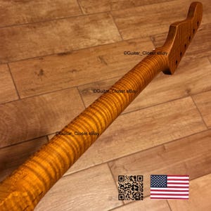 May include: A guitar neck with a flamed maple grain pattern. The neck is a warm amber colour and has tuning peg holes at the headstock. The text "Guitar Closet eBay" is visible on the neck. An American flag and a QR code are in the lower right corner.