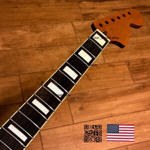 May include: A guitar neck with a brown headstock and a black fretboard with white inlays. The neck is angled towards the bottom right, with the headstock at the top. The text "guitar_set eBay" is visible. An American flag is in the bottom right.