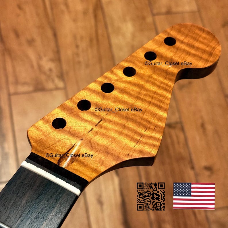 Puede incluir: Un clavijero de guitarra fabricado en madera de arce flameado de tono &aacute;mbar con un patr&oacute;n de veta ondulada. El clavijero incluye seis orificios circulares para clavijas, un diapas&oacute;n oscuro y una cejuela blanca. El texto dice Guitar_Closet eBay.