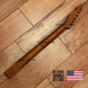 May include: A guitar neck made of wood with a dark brown finish. The neck has a headstock with six tuning peg holes and a fretboard. The wood grain is visible. The image also includes a QR code and a US flag.