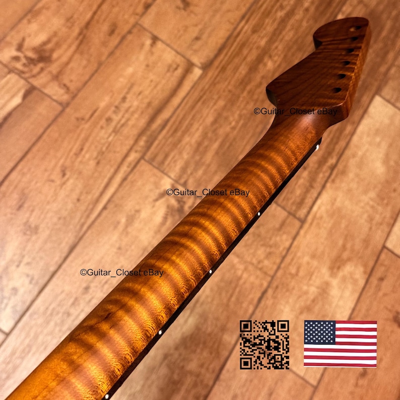 May include: A guitar neck crafted from brown flamed maple wood featuring a distinct tiger-stripe grain pattern. The headstock is angled with six tuner holes, and the side of the fretboard displays small white position markers along the edge.