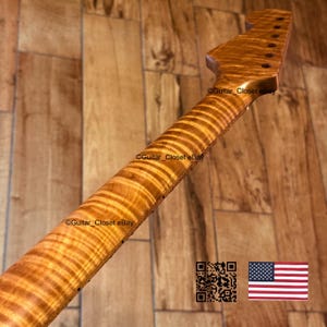 May include: A maple guitar neck with a flamed pattern. The neck has a natural wood finish and features tuning peg holes at the headstock. The fretboard has a striped pattern. The image includes a QR code and the American flag.