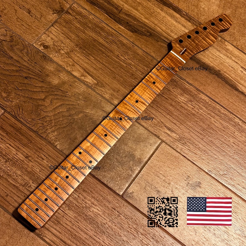 Pu&ograve; includere: Un manico per chitarra caratterizzato da una venatura del legno di acero fiammato marrone chiaro con finitura naturale. Il manico include una tastiera con segnatasti circolari scuri, tasti in metallo e una paletta con fori.