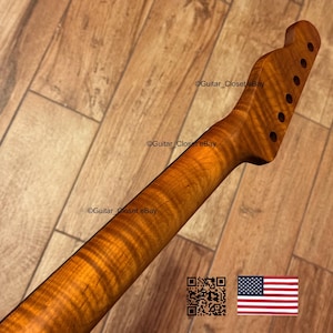 Puede incluir: Un m&aacute;stil de guitarra con acabado de arce flameado. El m&aacute;stil es de color &aacute;mbar c&aacute;lido con patrones de vetas de madera visibles. El clavijero tiene agujeros preperforados para las clavijas. La imagen incluye el texto "Guitar_Closet eBay" y un c&oacute;digo QR.
