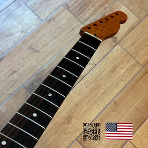 May include: A guitar neck with a dark brown fretboard and a light brown headstock. The fretboard has white dot inlays and silver frets. The headstock has six tuning peg holes. The image includes a QR code and an American flag.