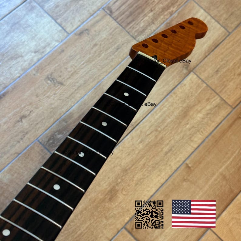 May include: A guitar neck with a dark brown fretboard and a light brown headstock. The fretboard has white dot inlays and silver frets. The headstock has six tuning peg holes. The image includes a QR code and an American flag.