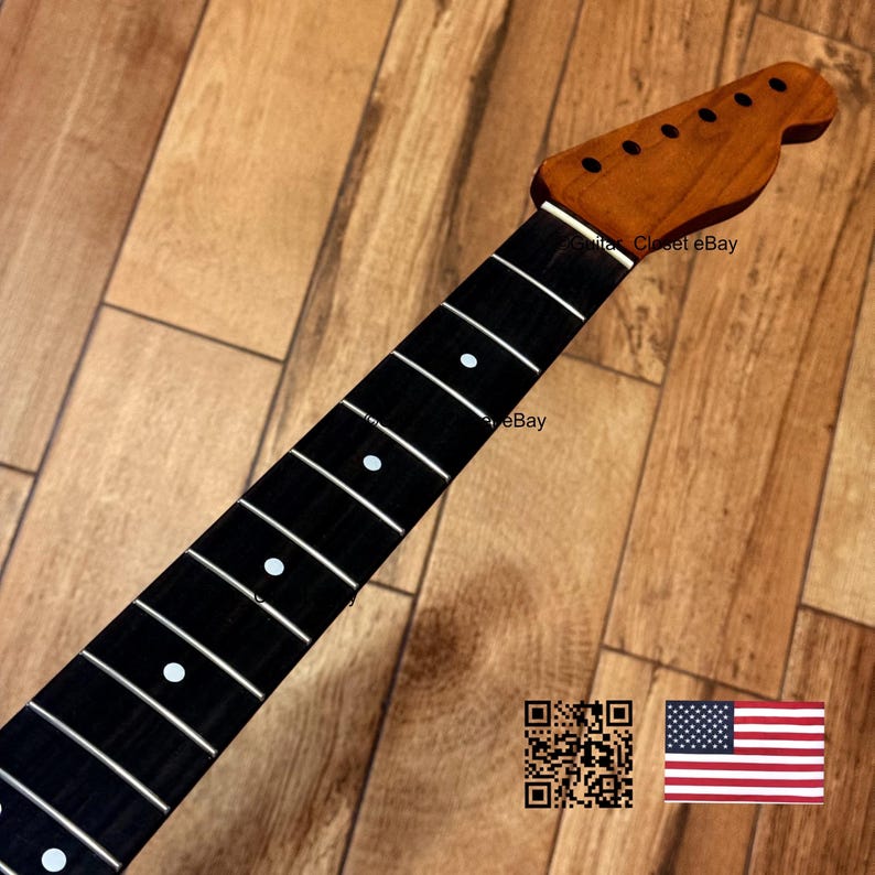 May include: A guitar neck with a dark fretboard and white dot inlays. The headstock is a lighter wood color with tuning peg holes. The neck is set against a wooden background. The image includes a QR code and a US flag.