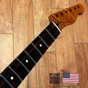 Puede incluir: Un m&aacute;stil de guitarra con un diapas&oacute;n marr&oacute;n oscuro y una pala marr&oacute;n claro. La pala tiene seis agujeros para las clavijas. El diapas&oacute;n tiene incrustaciones de puntos blancos. El m&aacute;stil es de madera y tiene un acabado brillante. La imagen tambi&eacute;n incluye un c&oacute;digo QR y una bandera estadounidense.