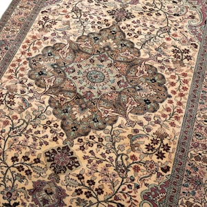 May include: A rectangular area rug featuring a cream-colored background with a central medallion and intricate floral patterns in shades of dusty rose, sage green, dark brown, and charcoal gray, framed by a detailed multi-layered decorative border.