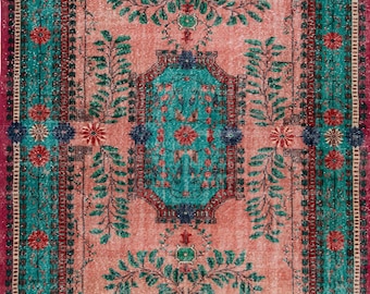 May include: A rectangular area rug featuring a salmon pink central field with a teal octagonal medallion. The design includes green leafy vine motifs, red and blue floral patterns, and a wide border in teal and magenta with floral accents.