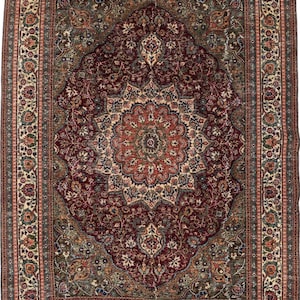 May include: A rectangular area rug featuring a deep burgundy central medallion surrounded by intricate floral and vine patterns in shades of olive green, cream, and navy blue, enclosed by a wide, detailed border with repeating motifs.