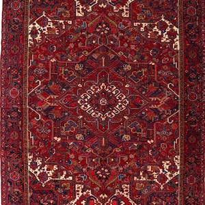 May include: A rectangular area rug featuring a deep red background with intricate geometric and floral patterns in navy blue, cream, and gold. The design includes a central medallion surrounded by symmetrical motifs and a wide, detailed border.