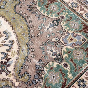 May include: A woven area rug featuring a complex pattern of floral and geometric motifs in shades of sage green, dusty rose, cream, and slate blue. The design includes a central field with intricate borders and a distressed, weathered texture.