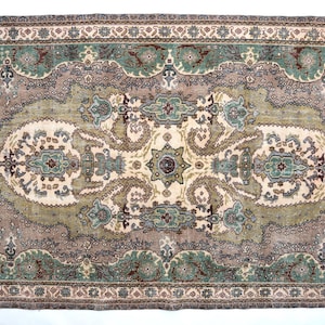 May include: A rectangular area rug featuring a central cream-colored medallion surrounded by intricate floral and paisley patterns in shades of sage green, dusty rose, and dark brown. The border displays a repeating geometric and floral motif.