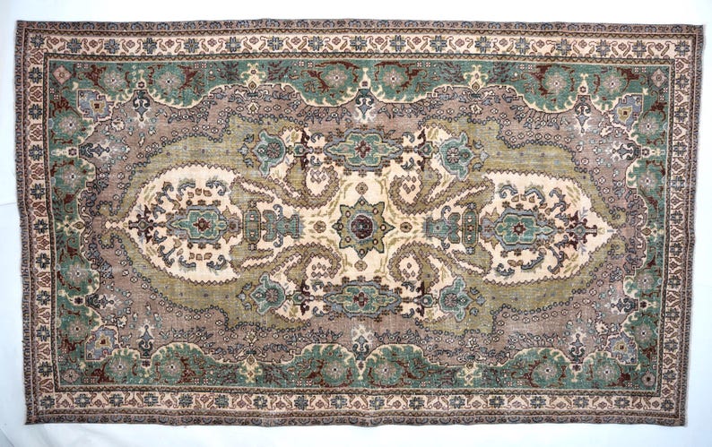 May include: A rectangular area rug featuring a central cream-colored medallion surrounded by intricate floral and paisley patterns in shades of sage green, dusty rose, and dark brown. The border displays a repeating geometric and floral motif.