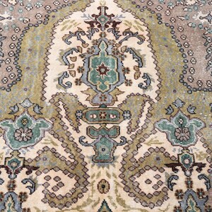 May include: A woven area rug featuring a central medallion and intricate floral motifs in shades of sage green, dusty rose, cream, and slate blue. The design includes symmetrical patterns with detailed borders and a weathered, textured appearance.