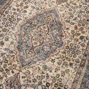 May include: A rectangular area rug featuring a central medallion design in shades of charcoal gray, muted peach, and cream. The surface is covered in an intricate floral pattern with vines and leaves, framed by a wide border with geometric motifs.