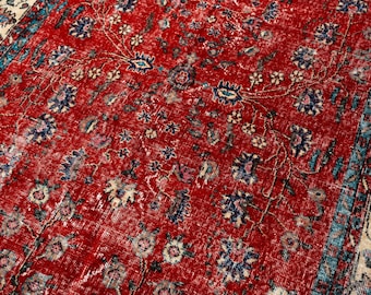 Könnte beinhalten: Nahaufnahme eines roten, abgenutzten Teppichs mit einem komplizierten Blumenmuster. Der Teppich hat ein rotes Mittelfeld mit blauen, cremefarbenen und rosa Blumenmotiven. Der Rand ist cremefarben mit blauen Akzenten.