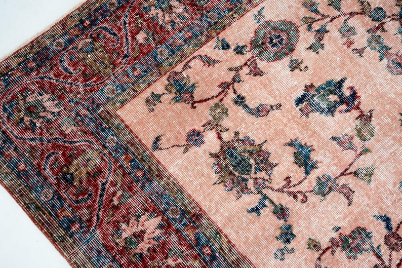 Pu&ograve; includere: Due tappeti antichi con motivi floreali. Un tappeto ha un campo color salmone con accenti floreali blu e verdi. L'altro tappeto ha un bordo rosso, blu e marrone con un design dettagliato. I tappeti sono posizionati ad angolo.