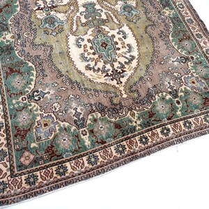 May include: A rectangular area rug featuring a central medallion design in shades of sage green, dusty rose, and cream. The rug displays an intricate floral and geometric pattern with a wide border containing repeating motifs in blue, brown, and tan.