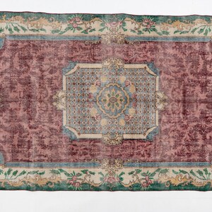 May include: Rectangular area rug with a distressed, vintage look. The rug features a central maroon field, framed by a light blue border and a cream-colored floral border. The rug's design includes floral and geometric patterns.