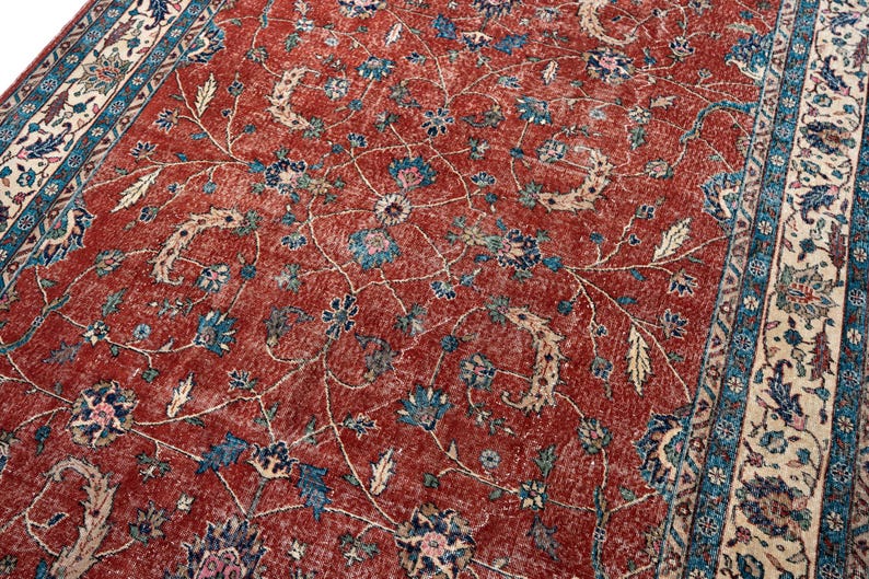 May include: A distressed, vintage-style rug with a rich red background. The rug features a detailed floral pattern in shades of blue, beige, and cream. The border has a complementary design. This rug is suitable for living rooms and bedrooms.