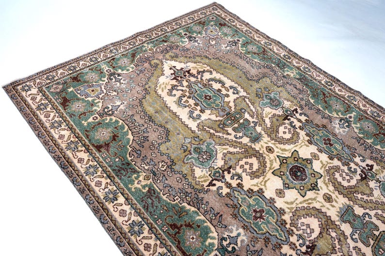May include: A rectangular area rug featuring an intricate central medallion and ornate border patterns in shades of sage green, dusty rose, cream, and dark brown. The woven textile displays symmetrical floral and geometric motifs throughout.